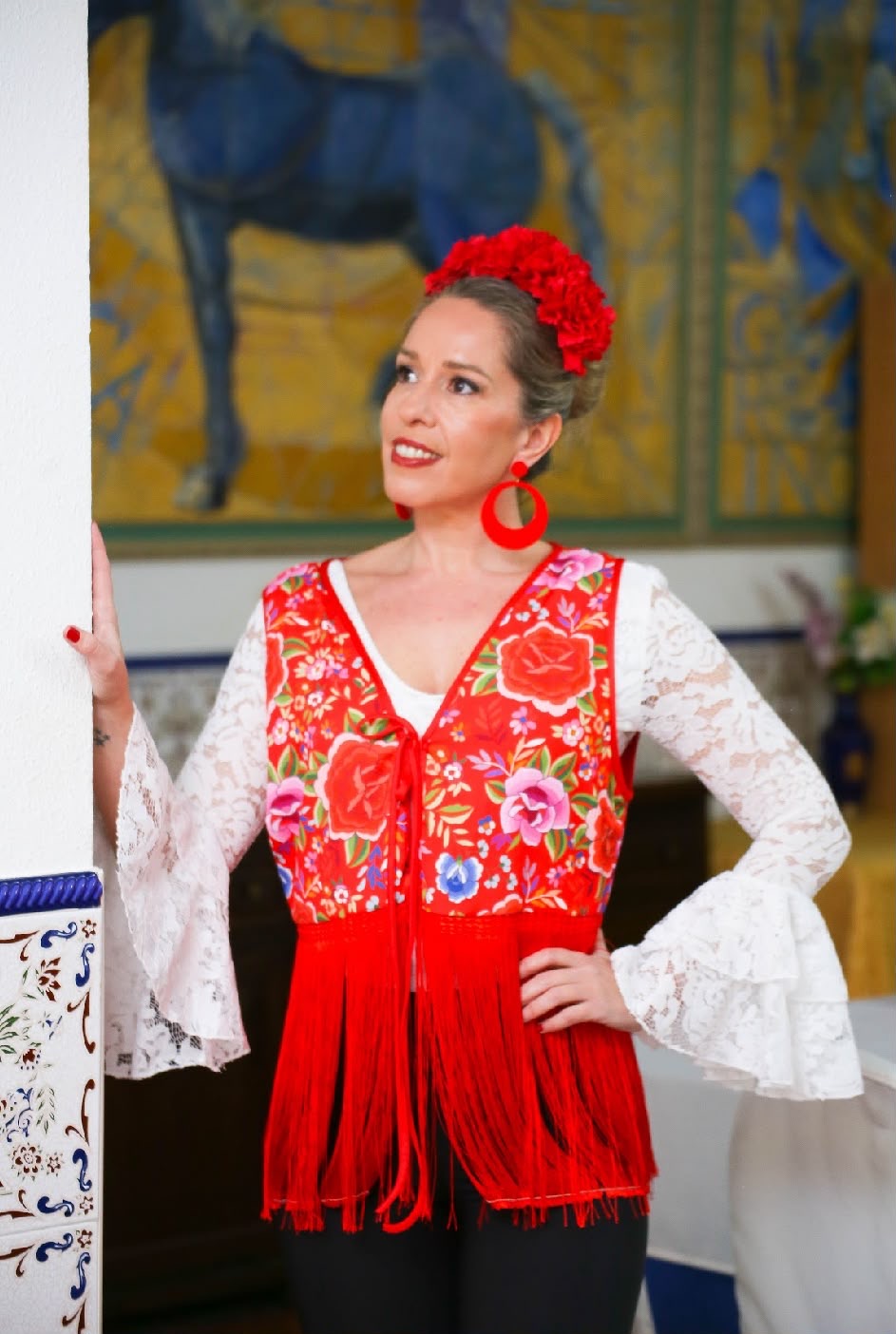 Gilet MANUELA rouge à fleurs multicolores et longues franges, porté sur une blouse blanche – tenue de flamenco