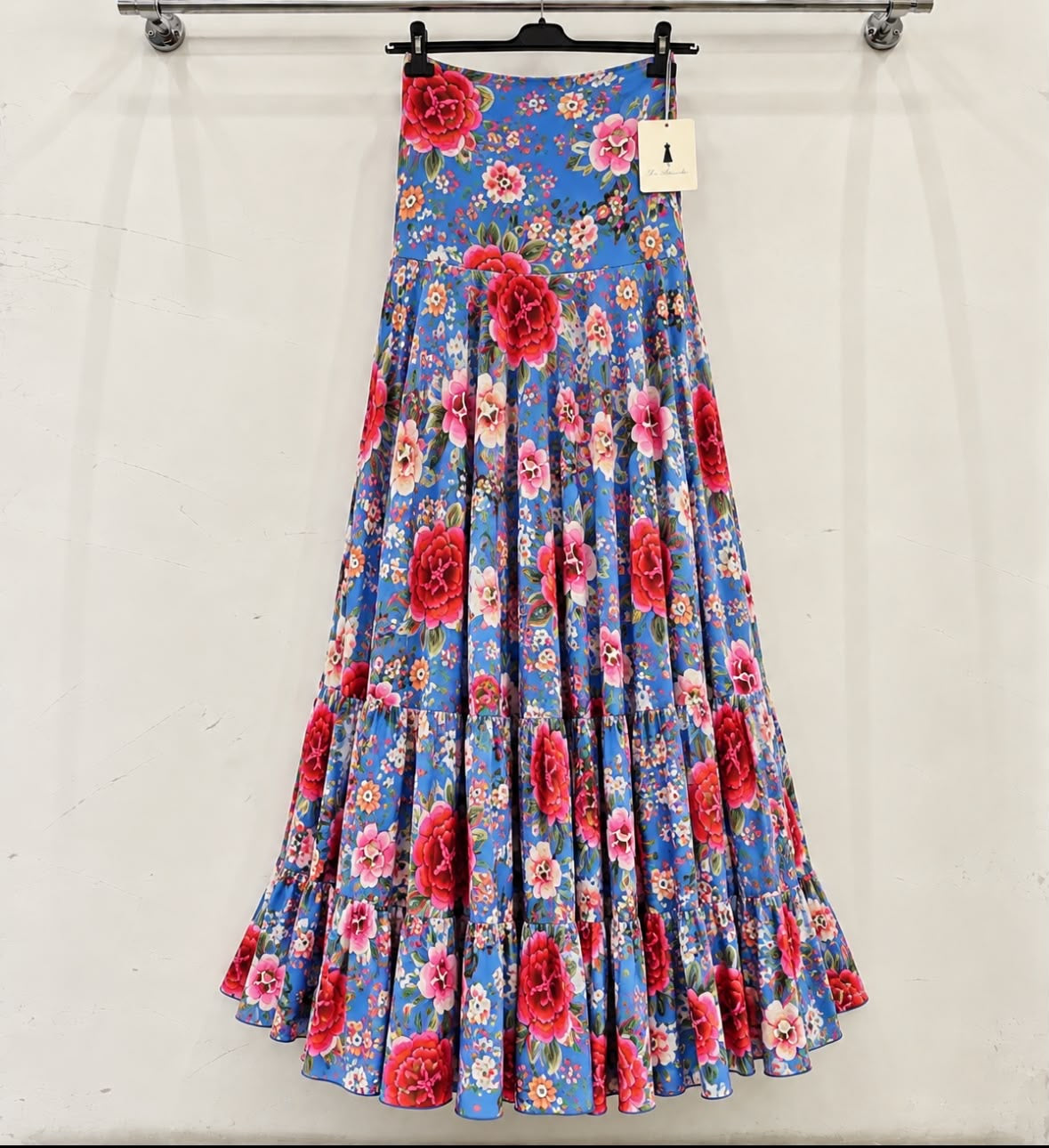 Jupe MILAGROS sur cintre, fond bleu à fleurs rouges et roses – tenue de flamenco